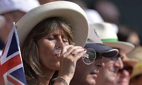 A Wimbledon spectator drinks while watching Andy Murray on his way to winning the men's final