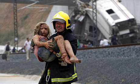 A firefighter carries an injured girl from the wreckage of the Santiago de Compostela train crash
