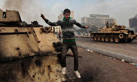 An Egyptian anti-government protester jumps from a burned armored personnel carrier