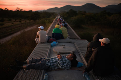 Central American migrants in Chiapas ride on top of a freight train