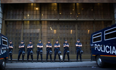 Riot police stand guard in front of a branch of a recently nationalised bank