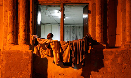 A man stands behind a window at his home in Havana