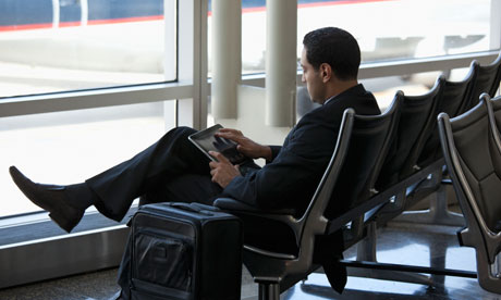 Business traveler using tablet computer in airport.