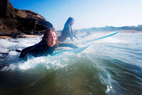Visit South West: People in the water with surfboards smiling.