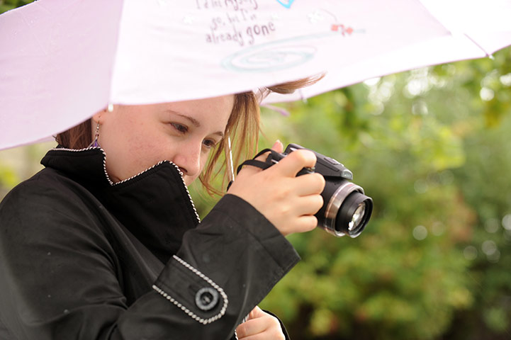 King's Cross : Romina shelters her camera and herself from the rain.