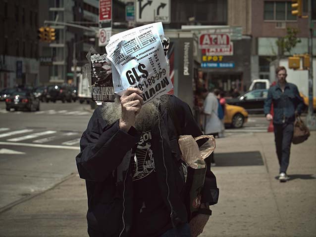 Panasonic G3 | NYC: Elderly bearded man covering face with leaflets on NYC street daytime