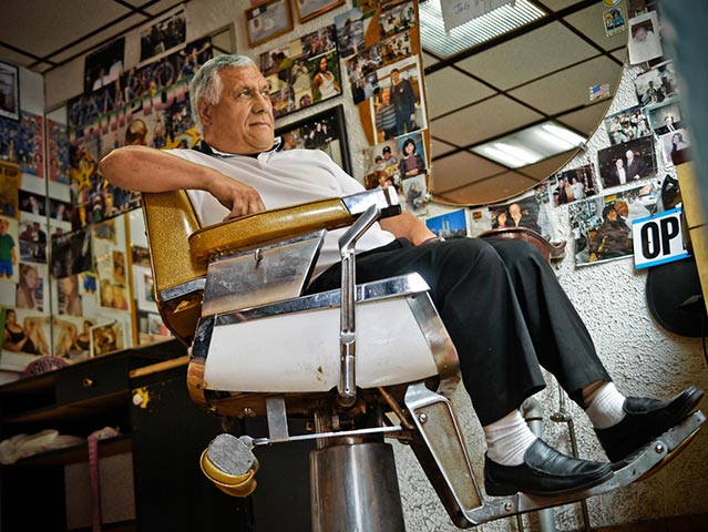 Panasonic G3 | NYC: Man relaxes in barber shop chair in room covered in photos