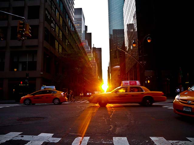 Panasonic G3 | NYC: Taxis drive past as sun sets in NYC, sun peaking between buildings