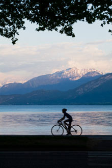 Silhouetted cyclist beside Lake Annecy 