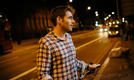 Man stood with bike in the street at night