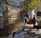 Un uomo cammina da manifesti di protesta a Londra Occupare campo esterno Cattedrale di St Paul