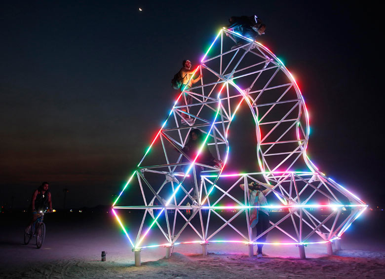 Participants climb an art installation before sunrise at the Burning Man 2013 arts and music festiva