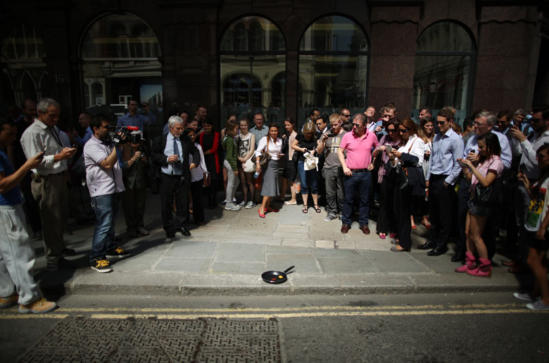 Crowds gather as a television crew try to fry an egg 