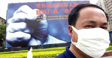A man wears a mask to protect himself against Sars, in front of a billboard in Beijing which reads: 'The Sars virus will be surely be conquered by our government under the leadership of the Communist party of China'