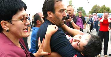 A man carries a wounded child from a school in Beslan, southern Russia, in which hundreds of people had been held hostage, after troops stormed it. Photograph: Ivan Sekretarev/AP