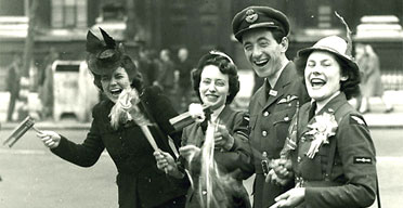 In Whitehall, London, an RAF officer and two members of the Women's Royal Air Force and a civilian celebrate on VE Day 1945