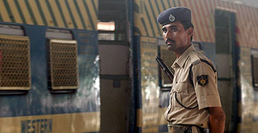 An Indian policeman stands guard at a railway station in Mumbai