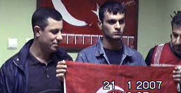 A video still showing Ogun Samast, who has confessed to the murder of Hrant Dink, holding a Turkish flag next to security officials