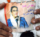 A cleaner at the mausoleum of the Bhutto family wears a picture of Benazir Bhutto
