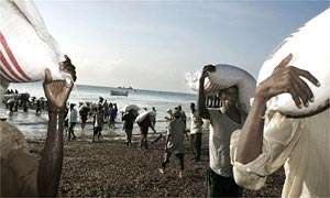 Somalian men unload sacks of sorghum provided by the World Food Programme (WFP) on Marka beach 