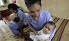 Five-month-old baby girls, are held by workers at an orphanage in Bac Ninh province, near Hanoi, Vietnam. Photograph: Chitose Suzuki/AP
