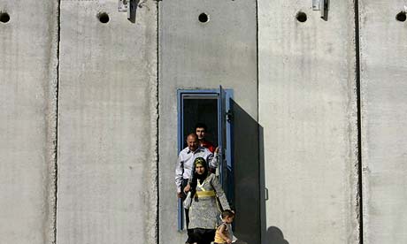 Palestinians walk through a door in a section of the barrier between Jerusalem and the West Bank