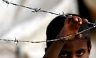 A Palestinian boy stands outside a makeshift tent