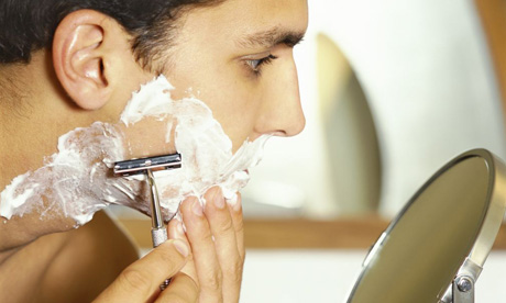 A young man shaving with a razor