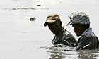 Two residents of Sidoarjo in eastern Java wade through chest-deep mud in search of possessions lost to the mud volcano