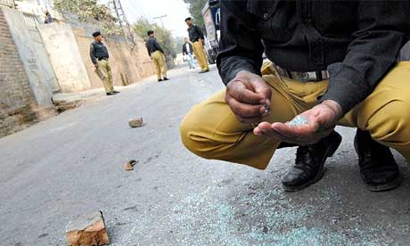Pakistani policemen inspect the site where a US aid worker was killed in Peshawar