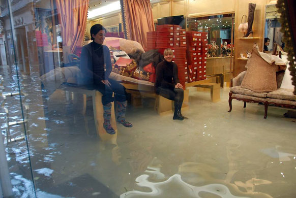 Gallery Flooding in Venice: Women sit on a table while water rises in their shoe shop in Venice