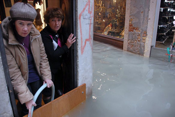 Gallery Flooding in Venice: Shopkeepers in Venice block the entrance of their shop with a wood panel