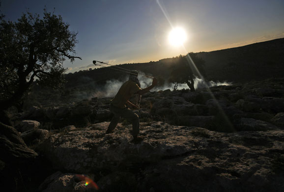 Gallery 24 hours in pictures: A Palestinian demonstrator uses a sling-shot to hurl stones at  police