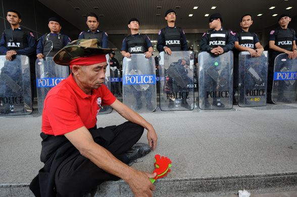 Gallery Thai politics: A pro-government protester sits in front of policemen