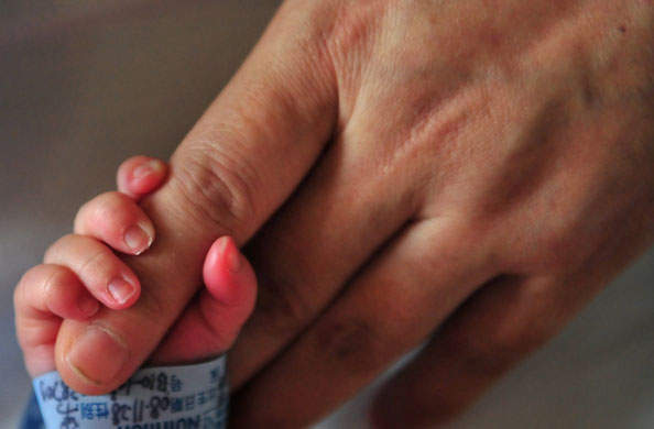 Gallery 24 hours in pictures : A newborn baby holds onto his mother's finger at a hospital  in Beijing