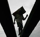 A labourer carries a sack of cement onto a ship  in Jakarta 