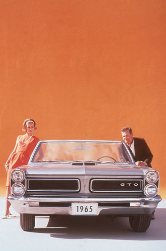 Gallery Michigan auto industry: A couple posing with  silver 1965 Pontiac GTO sports car