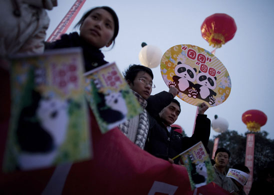 Chinese students and workers hold placards baring the names Tuan Tuan and Yuan Yuan during the send-off ceremony