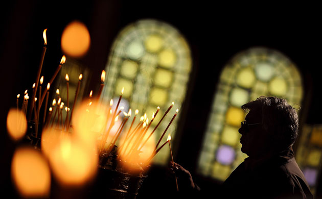 Gallery 24 hours in pictures: A man lights a candle during the Christmas Holly mass