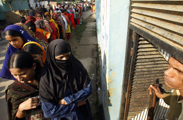 Gallery 24 hours in pictures: Dhaka, Bangladesh: A policeman stands guard as voters queue up