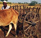 An Indian farmer tends his land in Dhule amid wind turbines at Suzlon Energy's windfarm