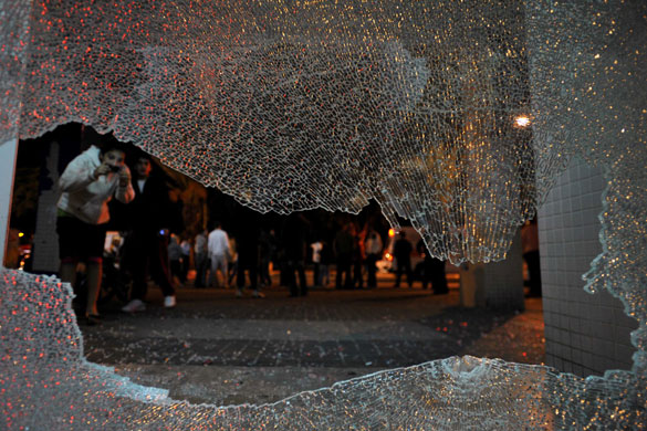 Gallery Gaza: An Israeli woman takes a picture of a window that was shattered