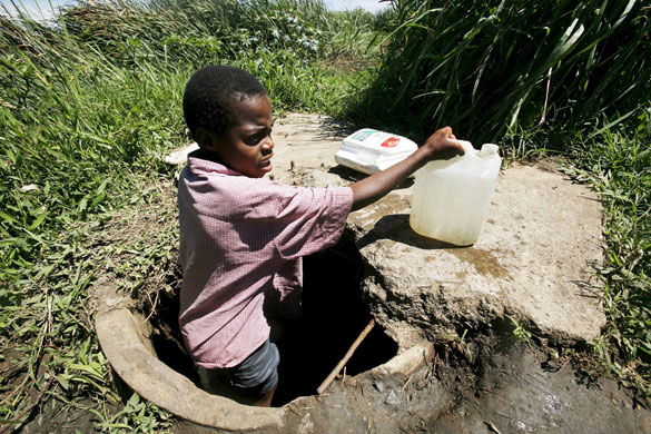 Gallery Zimbabwe cholera:  A young boy fetches water from an unprotected well in Harare