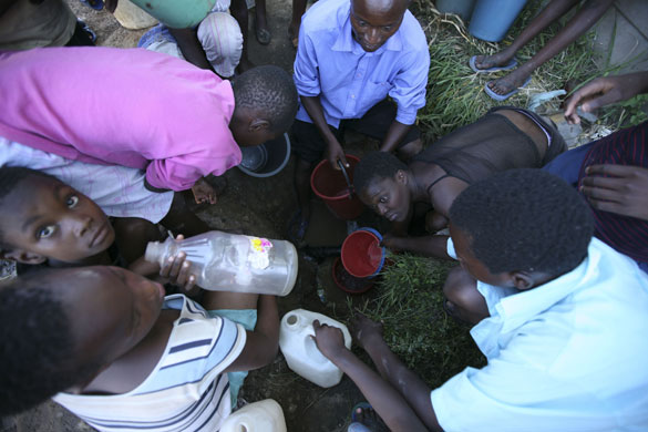 Gallery Zimbabwe cholera: Women and children wait to collect water from an underground source