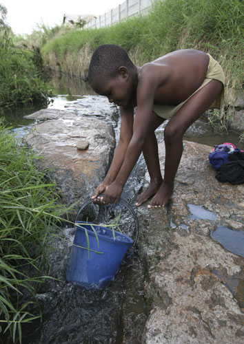 Gallery Zimbabwe cholera: A young boy fetches water from a river in Harare