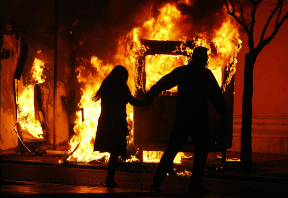 Gallery Riots in Athens: A couple runs to escape a fire at a booth during riots in Athens