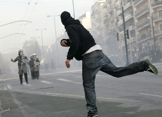 Gallery Riots in Athens: A protester throws stones at riot policemen during riots in Athens