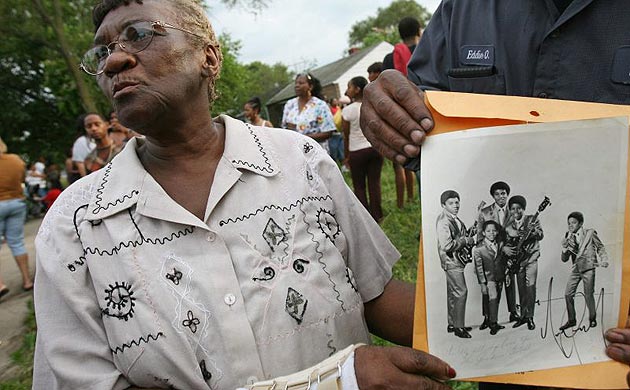 Mabele Moore, a former neighbour of Michael Jackson, holds an autographed photo of  the Jackson 5 outside Jackson's childhood home in Gary, Indiana 
