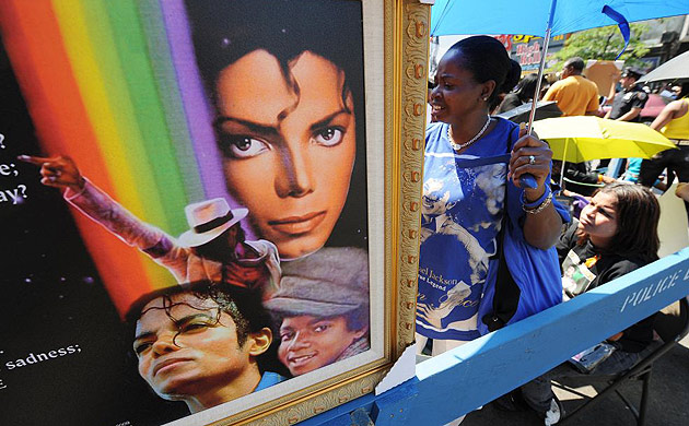 A woman stands near a painting in front of the Apollo theatre. Fans have been visiting the theatre since Jackson's death last Thursday