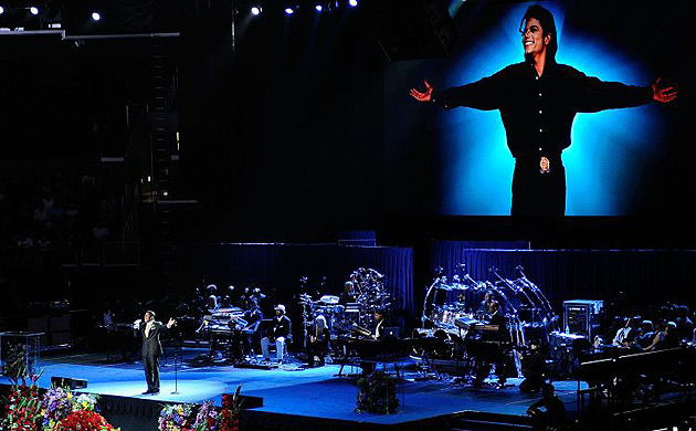 Jermaine Jackson sings as a video screen behind the stage shows an image of Michael Jackson